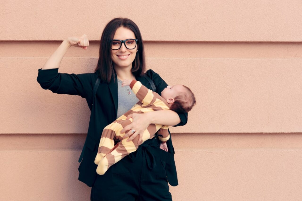 Woman dressed in typical office attire while holding a baby