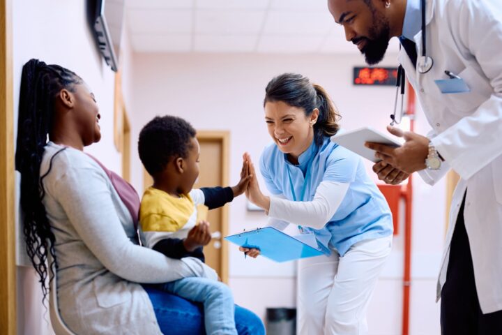 Healthcare employee high-fiving child and smiling