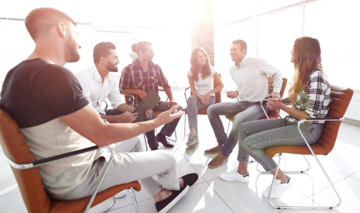 Happy men and women sitting in chairs