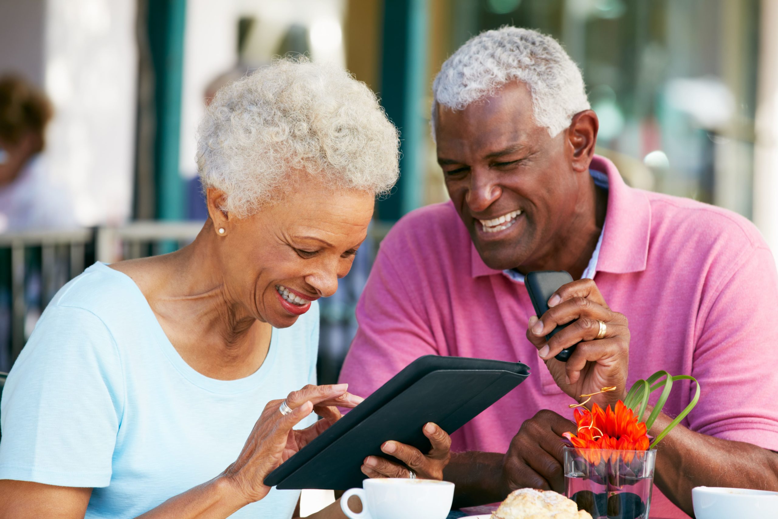 man and woman sitting at table looking at tablet